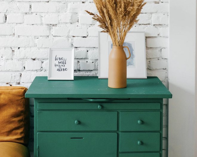 aesthetic looking living room with drawer, vase with flowers and frames as decor.